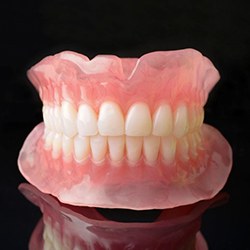 Full upper and lower dentures against dark background