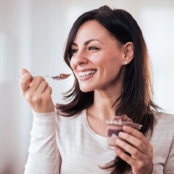 Woman eating pudding after dental implant surgery