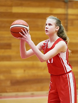 A teenage girl attempts a free throw while wearing a mouthguard