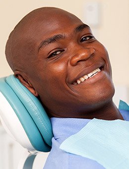 Smiling man in dental exam chair after wisdom tooth extraction