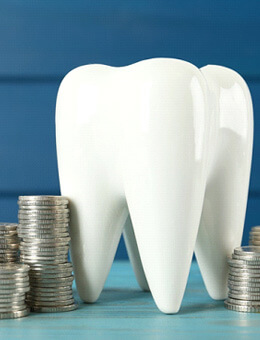 a large ceramic model of a tooth surronded by silver coins