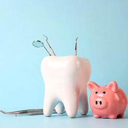 a pink piggy bank and tooth model with medical instruments on blue background