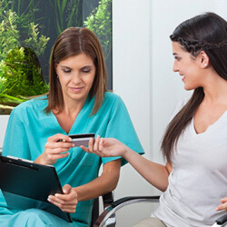 a woman using a credit card to pay the cost of cosmetic dentistry