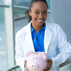 Smiling emergency dentist holding a piggy bank