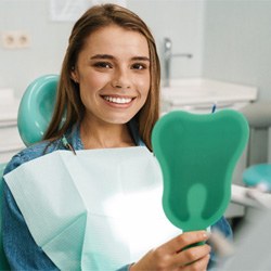 Female patient smiling and holding a mirror 