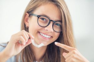 Confident, smiling teen holding Invisalign in Murphy