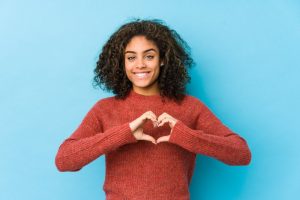 a girl smiling and using her hands to form a heart